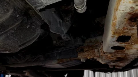 A mechanic works under a car chassis near rusty parts. Stock Footage 339491058