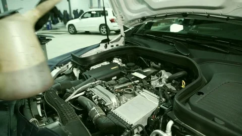 Mechanic in the workshop add oil to the engine under the hood of the car. Stock Footage 81138493