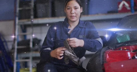 Mechanic wringing gray rag by red car raising gaze to camera, prepping repair as Stock Footage 330227394