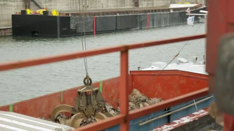 Mechanical claw loading scrap metal on a barge in an industrial harbor, Stock Footage 278142516
