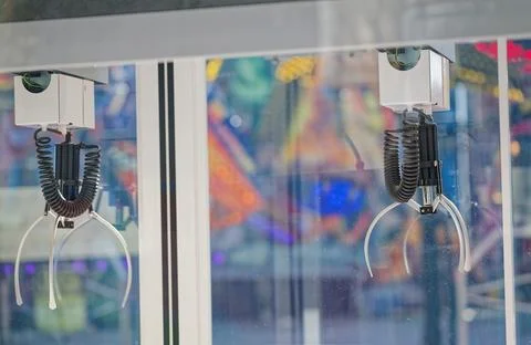 Mechanical claw machine grabber inside arcade game with colorful blurred ba.. Stock Photos