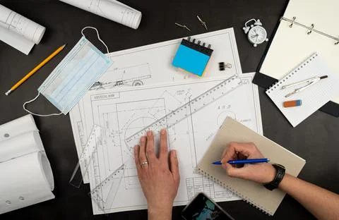 Mechanical drawing on sheets of paper. Hands on the table top view. Workflow  Stock Photos
