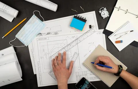 Mechanical drawing on sheets of paper. Hands on the table top view. Workflow of Stock Photos