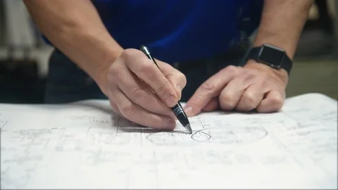 Mechanical Engineer Goes Over Blue Print Schematics with Pen and Hands Stock Footage 125914101