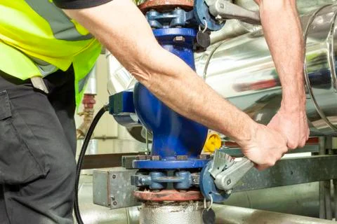 Mechanical engineer in high visibility vest opperating a valve Stock Photos