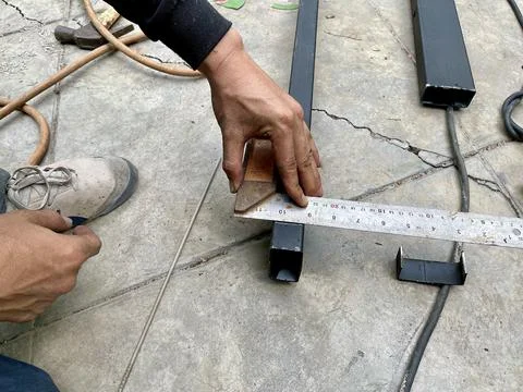 Mechanical engineer use ruler to measuring the metal frame before cutting it. Stock Photos