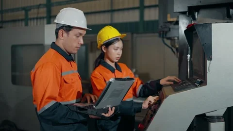 Mechanical engineers using a laptop to set up machine control systems in factory Video stock 330398097