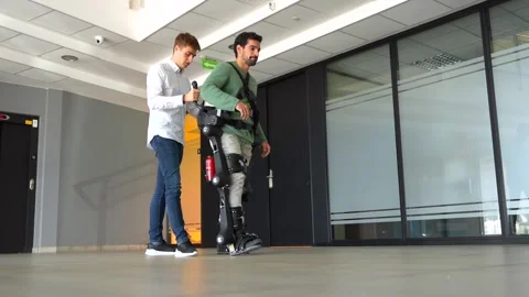 Mechanical exoskeleton, physiotherapist walking with disabled person with r.. Vídeo Stock 255217583