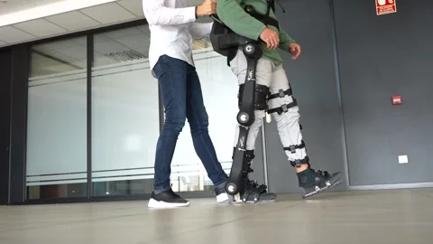 Mechanical exoskeleton, physiotherapist walking with unrecognizable disable.. Stock Footage 255217590