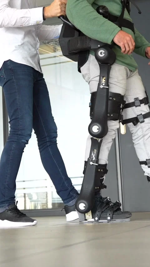 Mechanical exoskeleton, physiotherapist walking with unrecognizable disabled Stock Footage 258659316