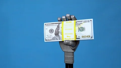 A mechanical hand holds a pack of dollars. A gray cyborg hand holds money on a Stock Footage 126661674