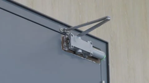 Mechanical hydraulic door closer installed on commercial metal door Stock-Footage 342087543
