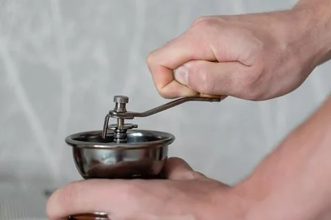 Mechanical machine for grinding coffee beans in the hands of a person Stock Photos