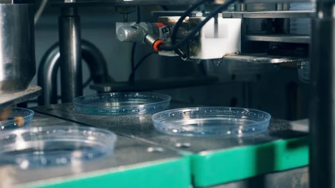 Mechanical machine works with plastic containers at a food factory. Food packing Video stock 111644427