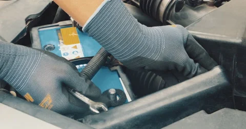 Mechanical man hand checking car battery with voltage meter replace old battery Stock Footage 168917414
