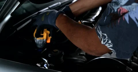 Mechanical man use electronic screwdriver fix car engine maintenance Stock Footage 219775090