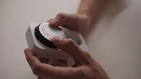 Mechanical timer switch being positioned by male sitting on white table Stock Footage 317537932