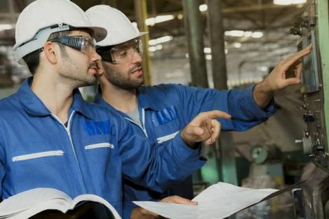 Mechanical worker with white safety helmet checking on production in a factory. Stock Photos