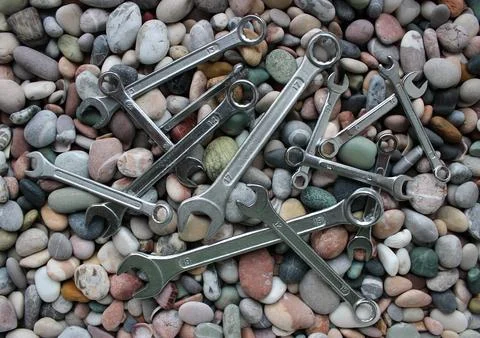 Mechanical wrenches of different sizes lying in disarray on stones Stock Photos
