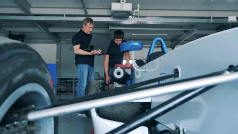 Mechanics are talking about a racing car in the garage Stock Footage 162877373