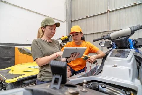 Mechanics consulting digital tablet while repairing personal watercraft Stock Photos