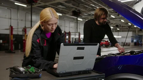 Mechanics during the inspection of the car engine. Diagnostic card on a laptop Stock Footage 240077149