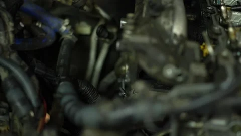 A mechanic's gloved hand works deep inside a complex engine bay, using a tool Stock Footage 345109749