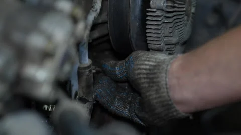 A mechanic's hand wearing a dirty work glove repairs a car engine compartment Stock Footage 345107189