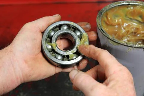 Mechanics Hands Applying multipurpose Lithium Grease To A Gearbox Bearing. Stock Photos