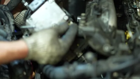 A mechanic's hands in dirty fabric work gloves carefully align or install a h Stock Footage 345109931