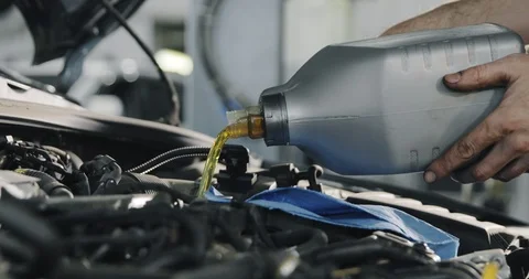Mechanic's Hands. Engine Oil Flows From The Canister Into The Engine Of A Car. Video stock 124979612