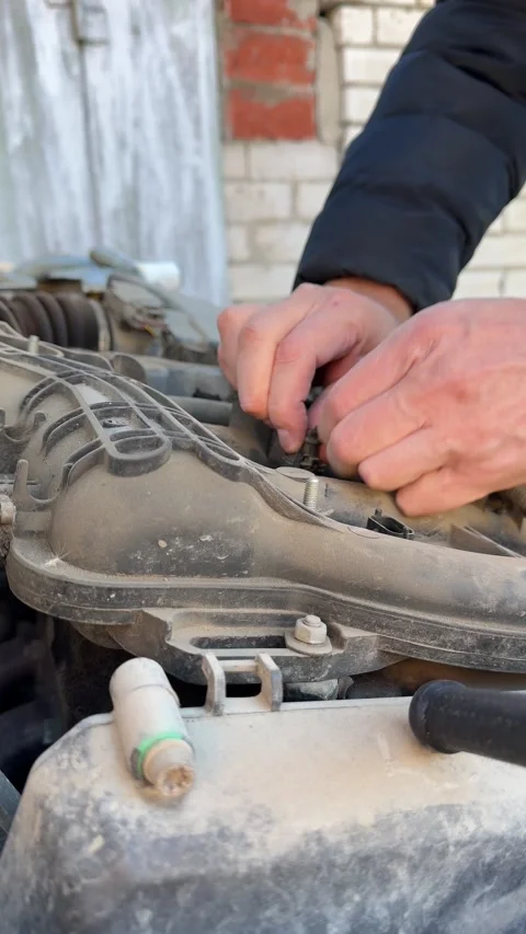 A mechanic's hands working on changing electrical wiring or ignition coils in Stock Footage 302471029