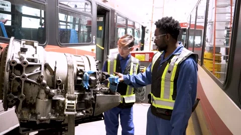 Mechanics inspecting bus engine in maintenance facility Stock Footage 221034109