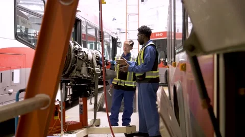 Mechanics inspecting bus engine in maintenance facility Stock Footage 221034135