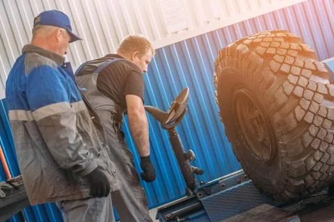 Mechanics Inspecting Large Tire in Workshop Environment Stock Photos