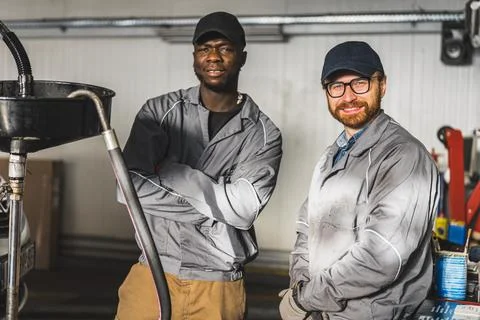 Mechanics posing for the camera while changing engine oil in an auto repair shop Stock Photos