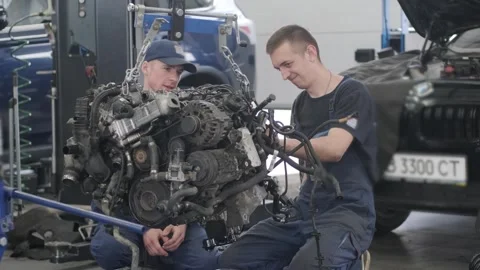 Mechanics removing engine using hoist in auto service workshop.	 Stock Footage 311580832