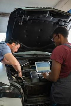 Mechanics repairing car engine using laptop in auto repair shop Stock Photos