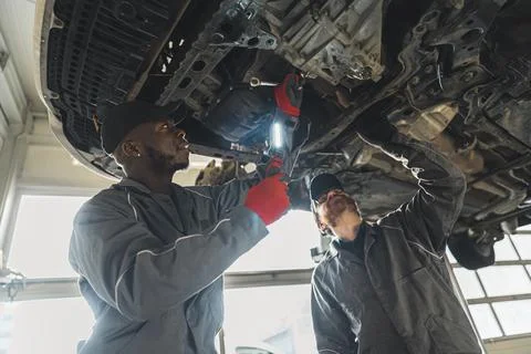 Mechanics replacing clutch using various tools, car workshop medium shot 스톡 사진