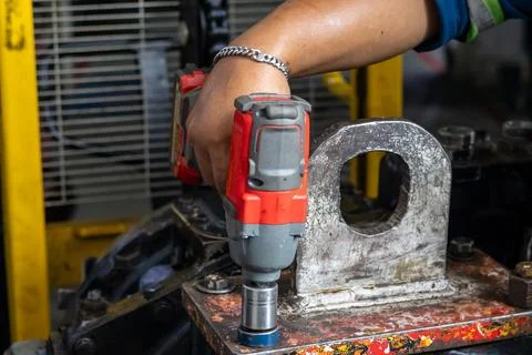 Mechanics secure heavy crane lifting bracket using cordless impact wrench i.. Stock Photos