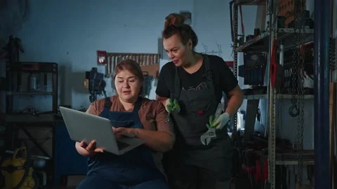 Mechanics troubleshoot machine issues while using a laptop in workshop Stock Footage 303801239