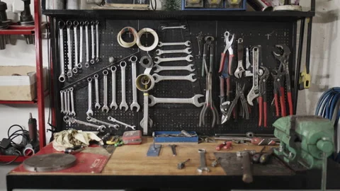 Mechanic's workbench with an organized tool pegboard and a green vise Stock Footage 331654096