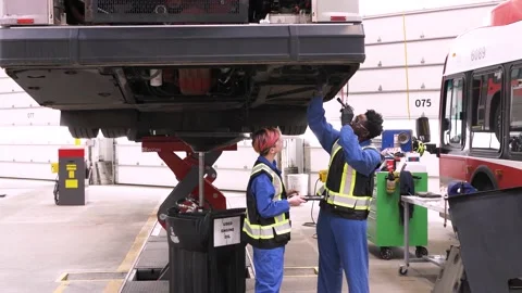 Mechanics working under bus in maintenance facility Stock Footage 221036000