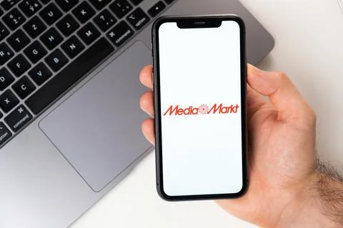 Media Markt mobile application on the smartphone screen. A mobile phone in a man Foto stock