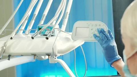 Medic in blue gloves on the panel adjusts the level of the chair Stock Footage 71633030