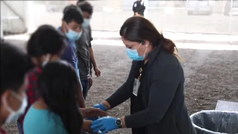 Medic checking child migrants hands at processing facility in Donna Texas Stock Footage 151251807
