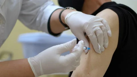 Medic in face mask inserts syringe and injects anti coronavirus flu vaccine. Stock Footage 157640343