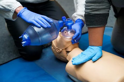 Medic in latex gloves using CPR technique on dummy in first aid class. Oxygen 写真素材