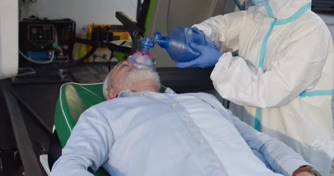Medic in personal protective equipment bringing old man in oxygen mask to the Stock Footage 158314472