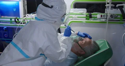 Medic in personal protective equipment saving life of old man in ambulance Stock Footage 158313574
